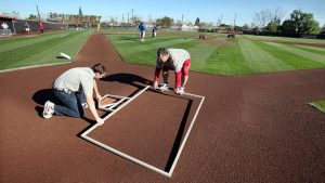 Groundskeeping crews go to a workshop and fix a local ball field.